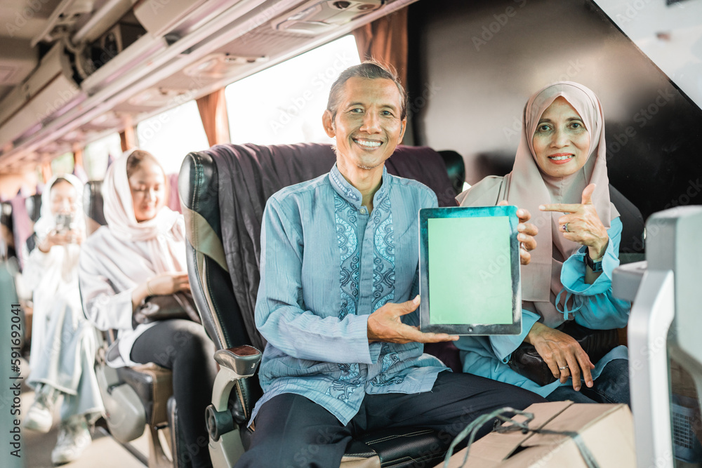 mature muslim couple using showing blank tablet screen to camera while riding a bus mature muslim couple using showing blank tablet screen to camera while riding a bus