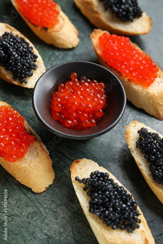 Tasty bruschettas with red and black caviar on color background
