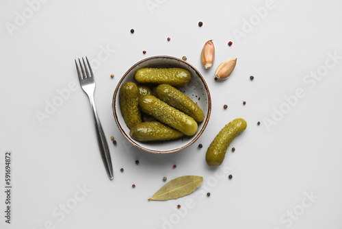Bowl with tasty fermented cucumbers on light background