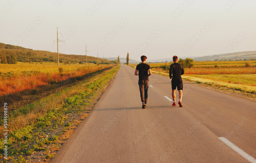 Fototapeta premium The two sportsmen running on the street. They look very nice in black sports suits.