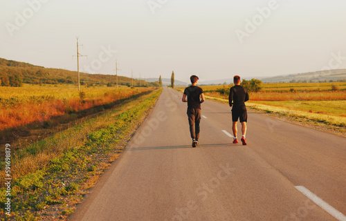 The two sportsmen running on the street. They look very nice in black sports suits.