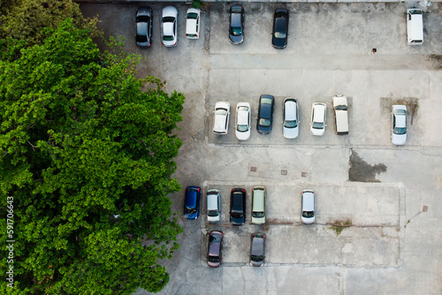 Aeriel view of cement floor parking lots with big trees on the left