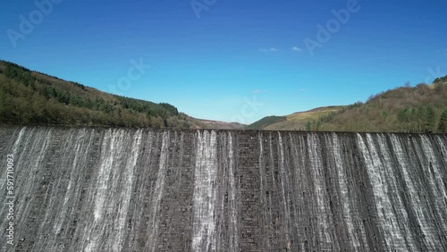 Dramatic aerial rising establishing shot of water cascading over the Derwent Dam, Peak District, UK, home of the Dam Busters practice during the second world war. photo