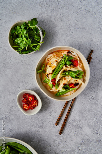 Veggie Gyoza Noodles with Sugar Snap Peas, Corainder and Chilli on grey surface photo