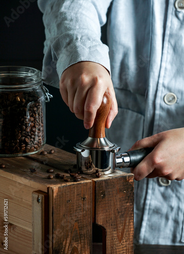 Barista hold portafilter and coffee tamper make coffee in coffee shop or cafe, dark backgrounds photo