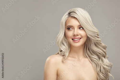 Beautiful lady with long wavy blonde hair lookinf aside on beige isolated with free copy space