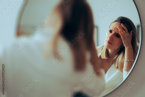 Canvas Print Frowning Woman Checking for New Wrinkles on her Forehead