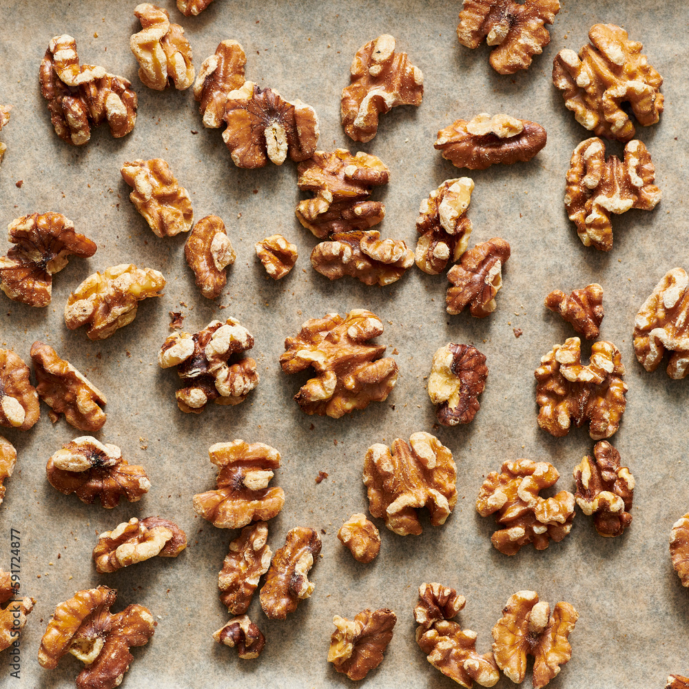 Toasted walnuts on parchment paper on a sheet pan. Toasted walnuts on parchment paper on a sheet pan.