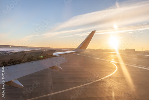 The plane is dressed for takeoff. Aircraft's wing and land seen through the illuminator. View from the window of the plane. Airplane, Aircraft. Traveling by air. Airplane flight at sunset or dawn. 