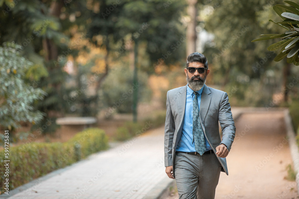 Confident Indian corporate man walking and giving expression at park. Confident Indian corporate man walking and giving expression at park.