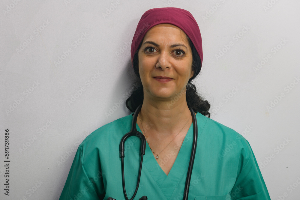 Health professional poses in studio against a grey wall, wearing green scrubs. Health professional poses in studio against a grey wall, wearing green scrubs.