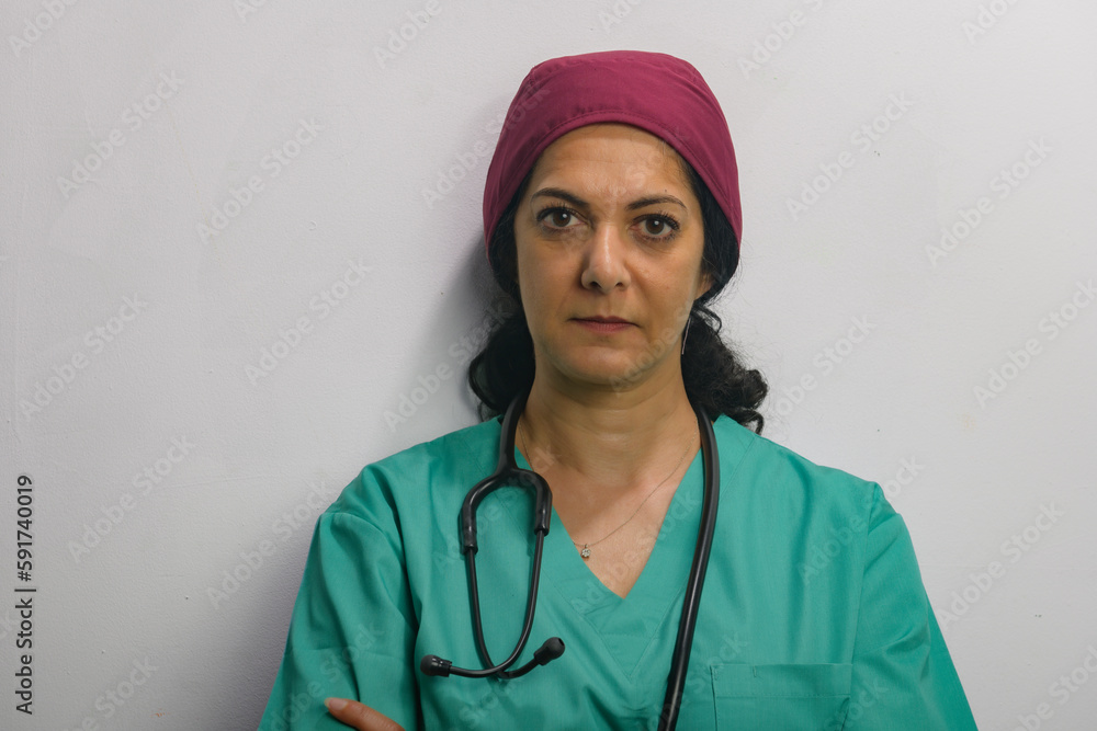 Health professional poses in studio against a grey wall, wearing green scrubs. Health professional poses in studio against a grey wall, wearing green scrubs.