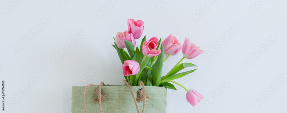 Pink tulips bouquet in green shopping bag on white background copy space banner Pink tulips bouquet in green shopping bag on white background copy space banner