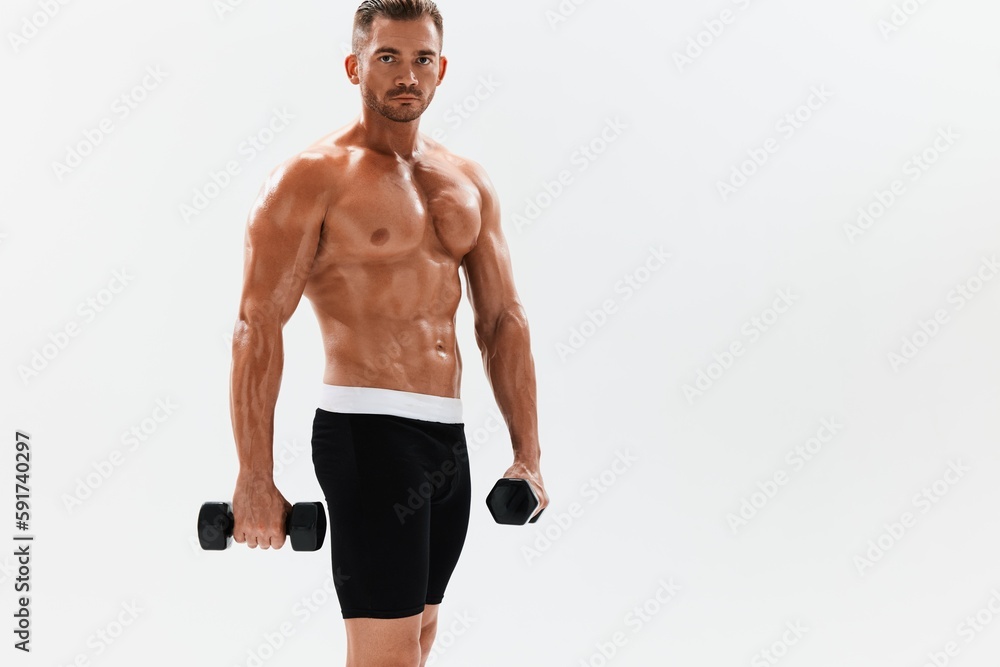 Man athletic body bodybuilder posing with dumbbells with naked torso abs full-length in the background, fitness class. Advertising, sports, active lifestyle, competition, challenge concept. Man athletic body bodybuilder posing with dumbbells with naked torso abs full-length in the background, fitness class. Advertising, sports, active lifestyle, competition, challenge concept.