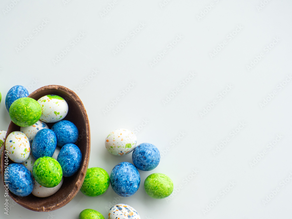 Sweet Easter concept. Blue, white and green chocolate easter eggs with sweets on white background with copy space. Design for a greeting card for the Easter holiday. Flat lay. Preparation for holiday Sweet Easter concept. Blue, white and green chocolate easter eggs with sweets on white background with copy space. Design for a greeting card for the Easter holiday. Flat lay. Preparation for holiday