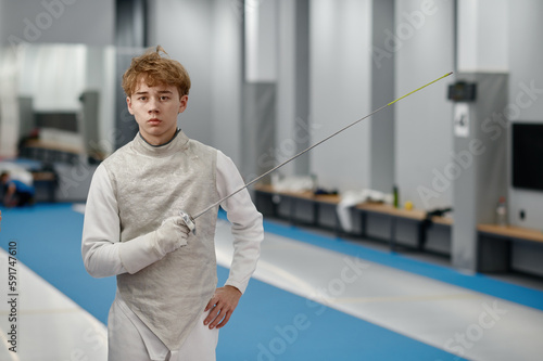 Photography Portrait of teenager fencer wearing white fencing costume with sword