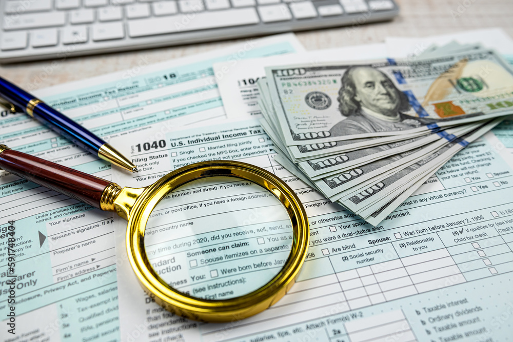 dollar with magnifying glass on blank 1040 individual income tax form dollar with magnifying glass on blank 1040 individual income tax form