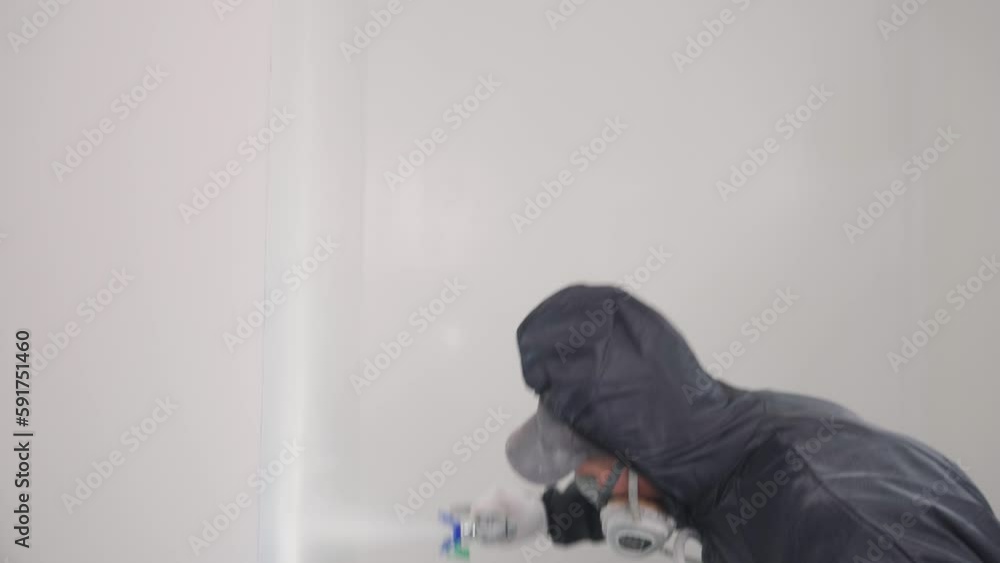 Painter builder man in protective gear works. Paints the wall with an airless spray. Finisher worker Painter builder man in protective gear works. Paints the wall with an airless spray. Finisher worker
