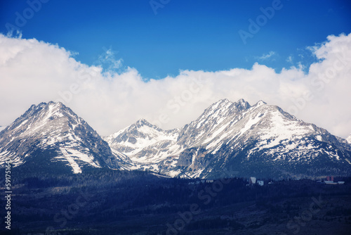 nature background of mighty high tatra ridge in spring at high noon. snowcapped rocky peaks beneath a cloudy sky © Pellinni