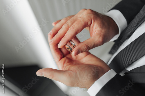 On a man's palm are two wedding rings. The groom holds the rings. Wedding tradition. Gold rings lie on a man's palm.