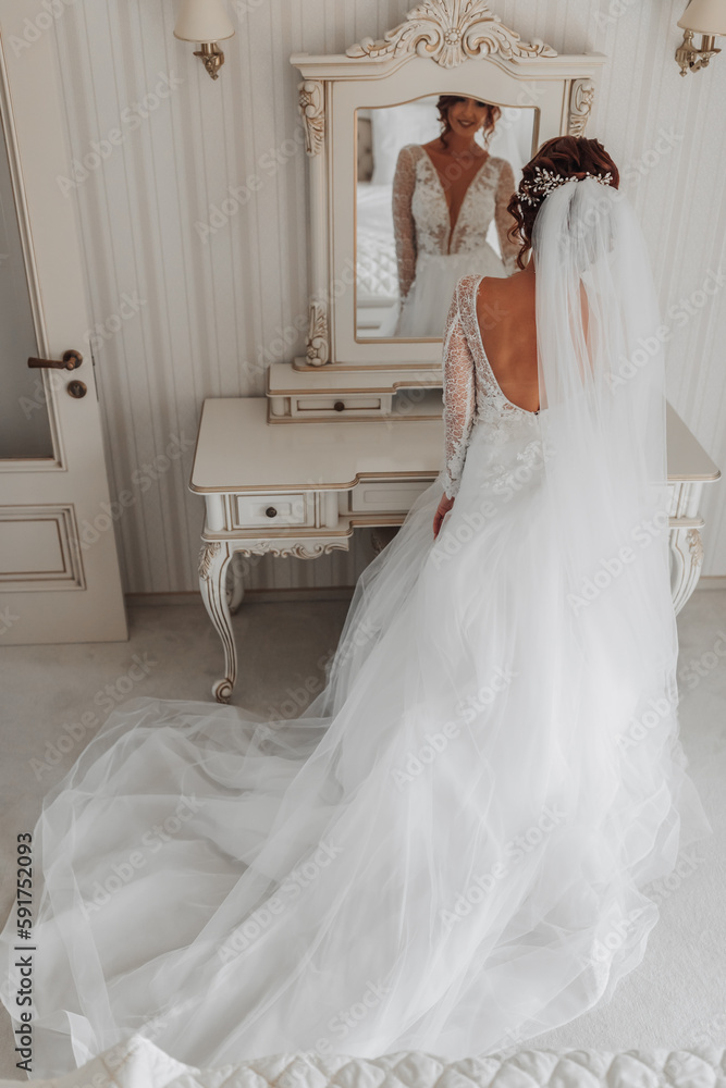 The bride in a beautiful dress holds the train of the dress in her hands. Wedding. wedding bouquet Morning of the bride. A happy bride is waiting for the groom. The bride in a beautiful dress holds the train of the dress in her hands. Wedding. wedding bouquet Morning of the bride. A happy bride is waiting for the groom.