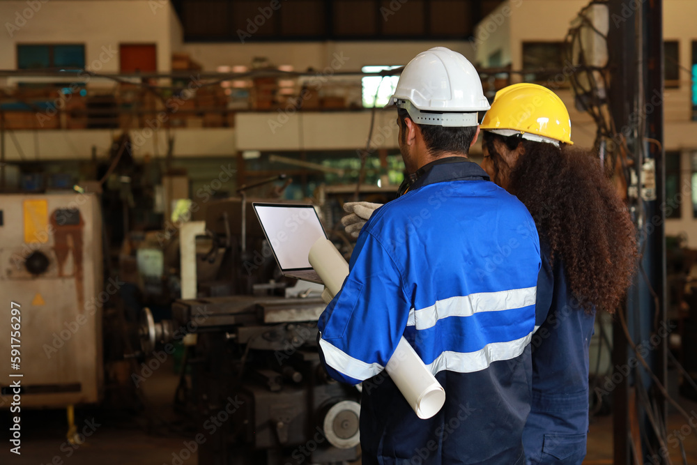 Rear view architect or worker checking at heavy industry manufacturing factory with walkie talkie radio and blueprint. Multiethnic business manager looking in future with warehouse factory building Rear view architect or worker checking at heavy industry manufacturing factory with walkie talkie radio and blueprint. Multiethnic business manager looking in future with warehouse factory building