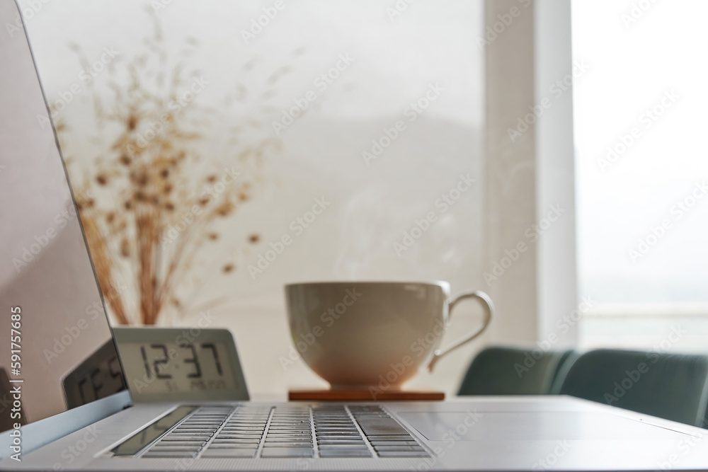 Modern working laptop on the table with coffee cup and digital clock. Time for coffee break Modern working laptop on the table with coffee cup and digital clock. Time for coffee break