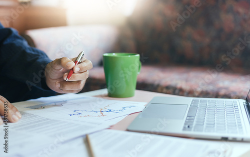 Asian businessman working at home using laptop with data from chart in paperwork working online and meeting with business partner to plan strategy of marketing and investment
