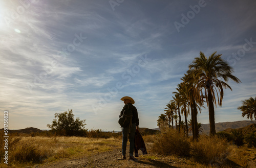 Rear view of adult man in cowboy hat walking on desert. Almeria, Spain © WeeKwong