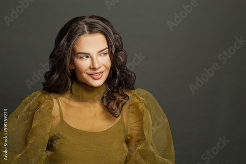 Cheerful fashion model woman with makeup and dark hair against black studio wall background