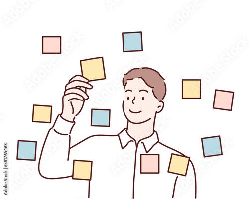 Focused young male employee writes ideas on sticky note on glass wall in office. Hand drawn style vector design illustrations.