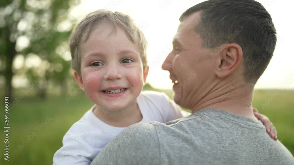 Happy family. Father and son are playing in the park. Baby in the arms of his father. Cheerful baby boy with father walk outdoors in the park. A smile on a child's face. Family team outdoors in park Happy family. Father and son are playing in the park. Baby in the arms of his father. Cheerful baby boy with father walk outdoors in the park. A smile on a child's face. Family team outdoors in park