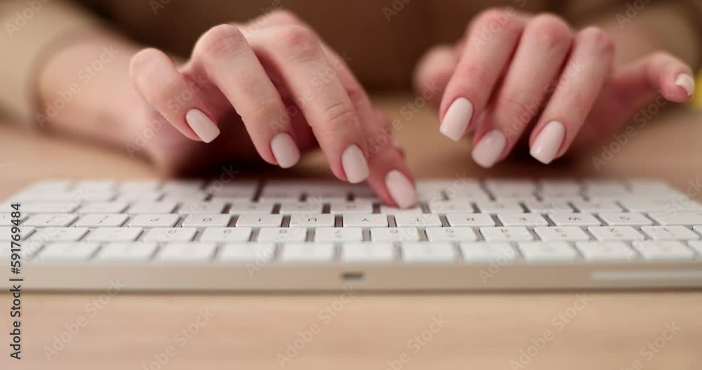 Hands of woman with neat manicure typing on white keyboard sitting at wooden table. Female freelancer writes article on computer slow motion Hands of woman with neat manicure typing on white keyboard sitting at wooden table. Female freelancer writes article on computer slow motion