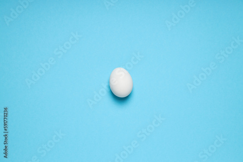White egg on blue background, space for text