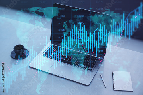 Close up of laptop, coffee cup and notepad on desktop with glowing candlestick forex chart on blurry background. Trade, stock and global finance concept. Double exposure. © Who is Danny