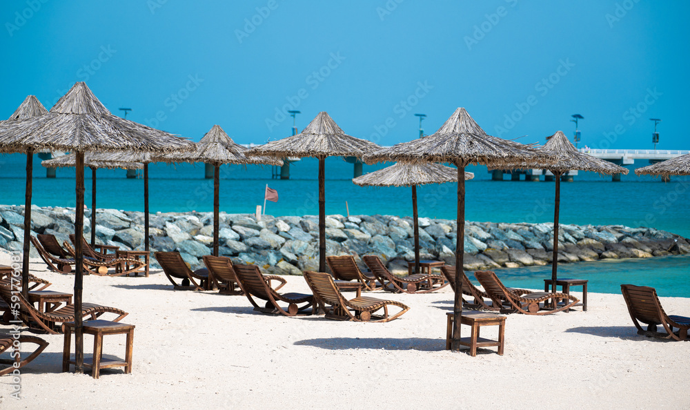 Sunbeds and umbrellas at Beach. Tropical beach, sunbeds and palm tree umbrellas. Vacation Concept