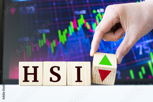 A hand rotates a wooden cube to indicate the fall or rise of the Chinese Stock Index Hang Seng HSI photo