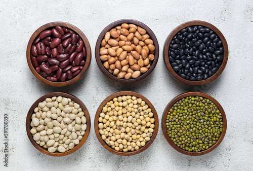 top view of red kidney beans, peanuts, black kidney beans, white kidney beans, soybean and mung beans in wooden bowls. cereals collection