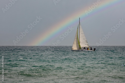 Barca a vela in mare, con arcobaleno