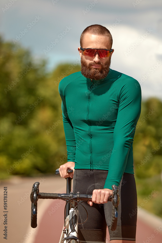Portrait of a cyclist on the background of the sky, a man in a cycling suit with goggles cycling hobby, cycling around the city, training cardio on a bike Portrait of a cyclist on the background of the sky, a man in a cycling suit with goggles cycling hobby, cycling around the city, training cardio on a bike