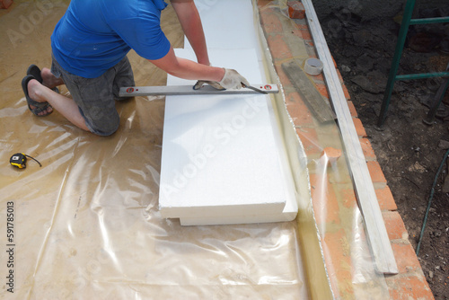 Contractor insulating house foundation floor with rigid foam board insulation with waterproof membrane. Insulated foam sheets for house warm floor foundation. photo