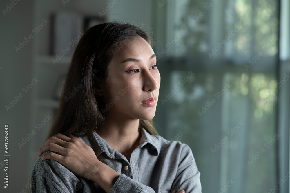 Portrait of sad and worried young Asian woman in living room