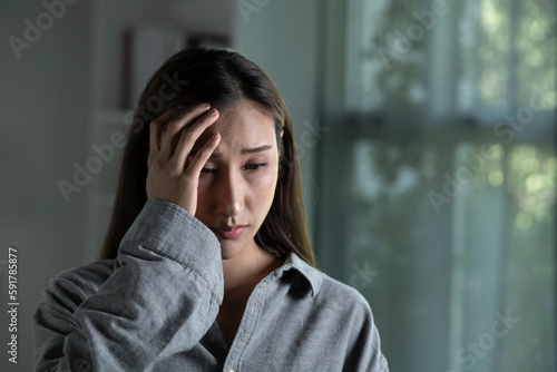 Portrait of sad and worried young Asian woman in living room