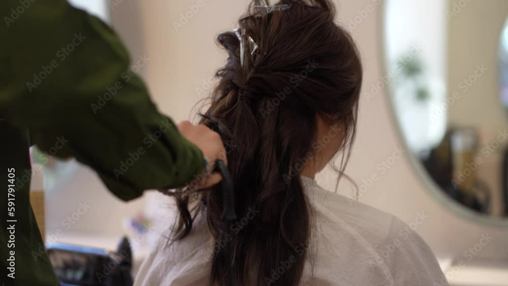 女性の髪にヘアアイロンをかける男性美容師 女性の髪にヘアアイロンをかける男性美容師