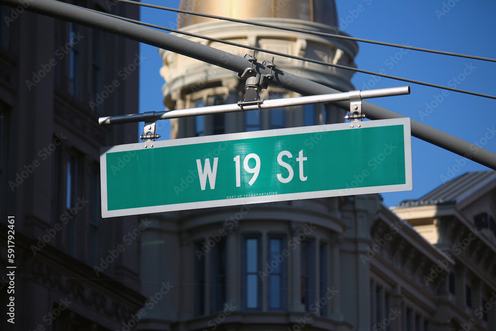 Obraz premium Green big West 19th Street sign hanging on a arch pole in the streets of midtown Manhattan