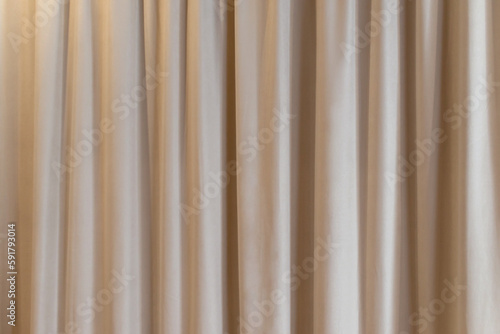 Beige curtain fabric texture and background. Large wall curtain. Curtain for hotel presentations. Cream colored cloth. 