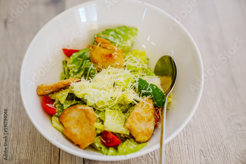 traditional Caesar salad with chicken in a white plate.