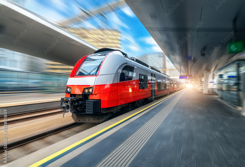 Naklejka premium Red high speed train in motion on the railway station at sunset. Fast modern intercity train and blurred background. Railway platform. Railroad in Austria. Commercial and passenger transportation 