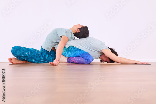 Two girls doing yoga, one performing Paschimottanasana pose and the other on top