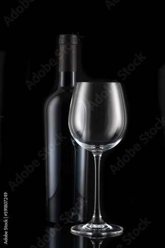 A bottle of wine and a wine glass in front of a black background